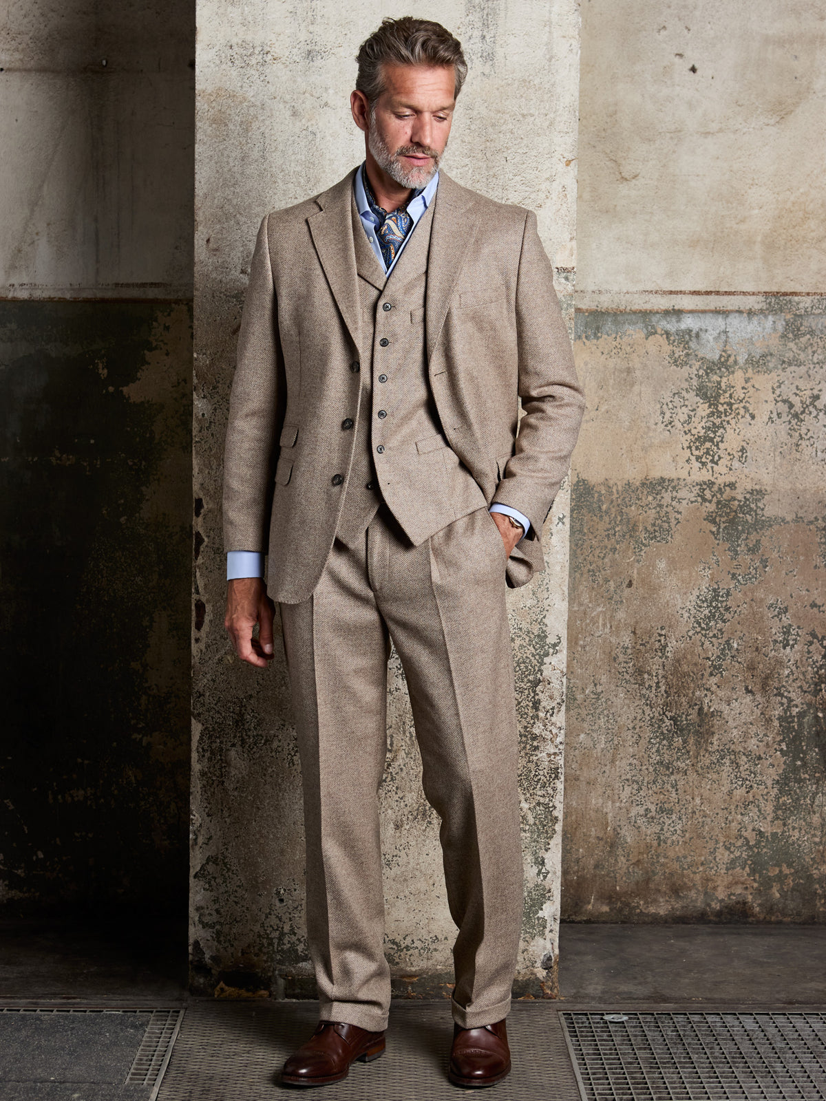 Tweed-Anzug Fischgrät Moon Tweed Oatmeal Dreiteiler am Model, Frontalansicht vor Betonwand — John Crocket