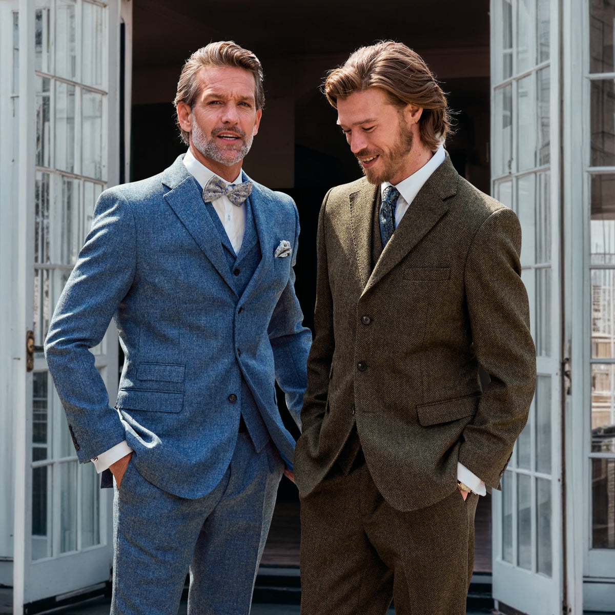 Due uomini in abiti di tweed, a sinistra blu con gilet e papillon, a destra marrone oliva con cravatta – John Crocket