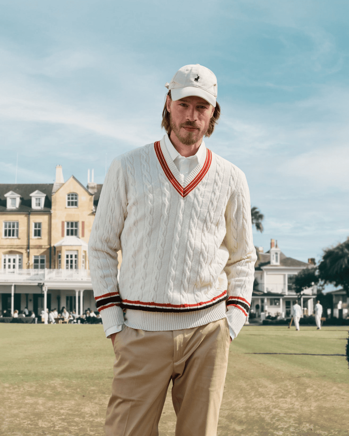 Homme en pull de cricket crème à torsades et rayures rouges et noires sur une pelouse – John Crocket