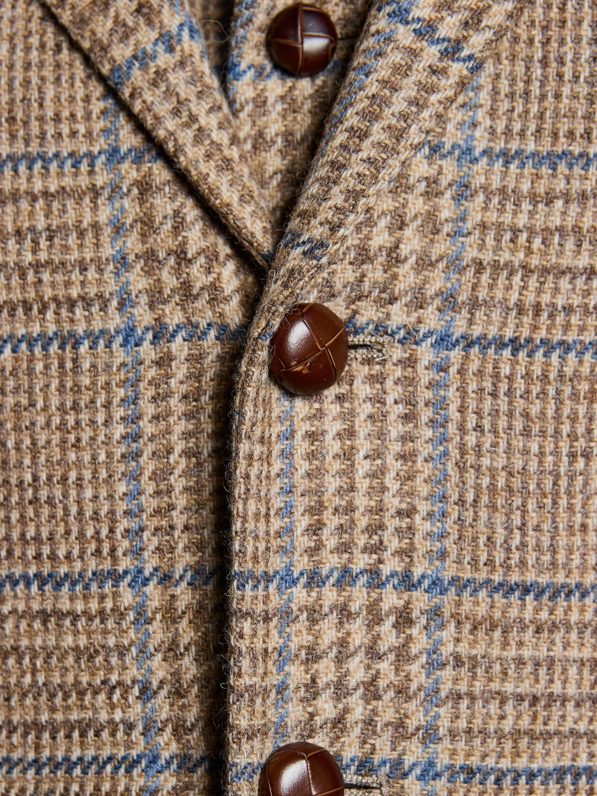 Tweed jacket in Prince of Wales check, Magee Tweed, Sand, detail view of the leather buttons – John Crocket