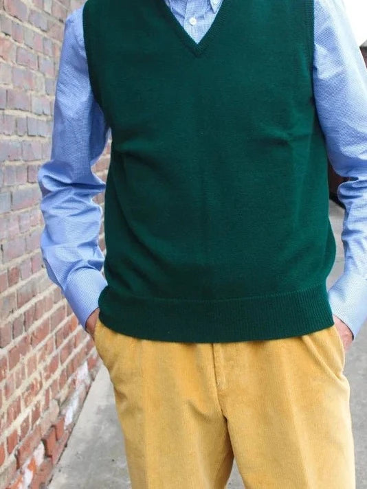 Lambswool slipover in Bottle, worn by a model with a light blue shirt and mustard yellow corduroy trousers – John Crocket