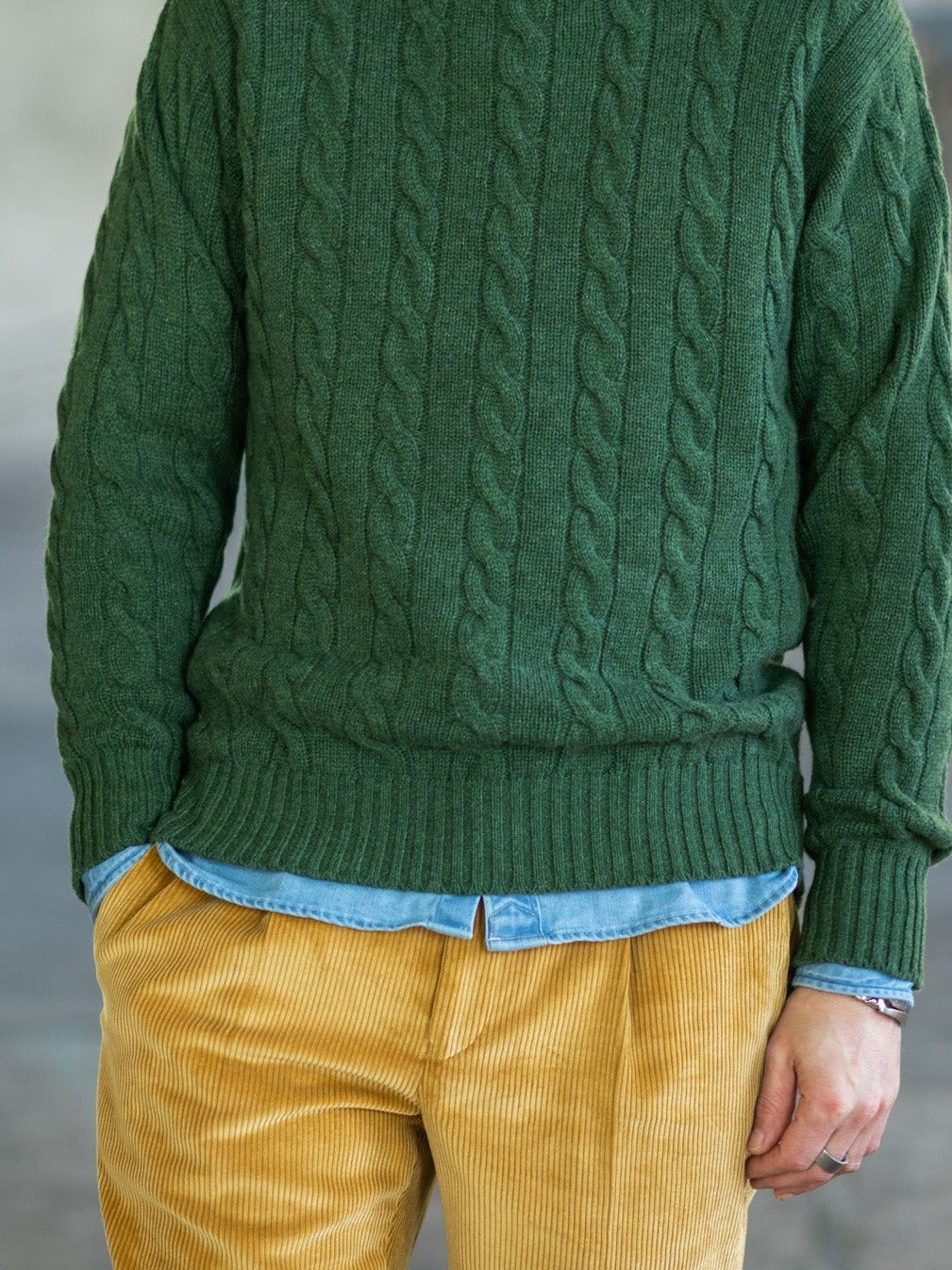 Cashmere cable knit jumper (6-ply) in Serpentine (green), worn over a denim shirt – John Crocket